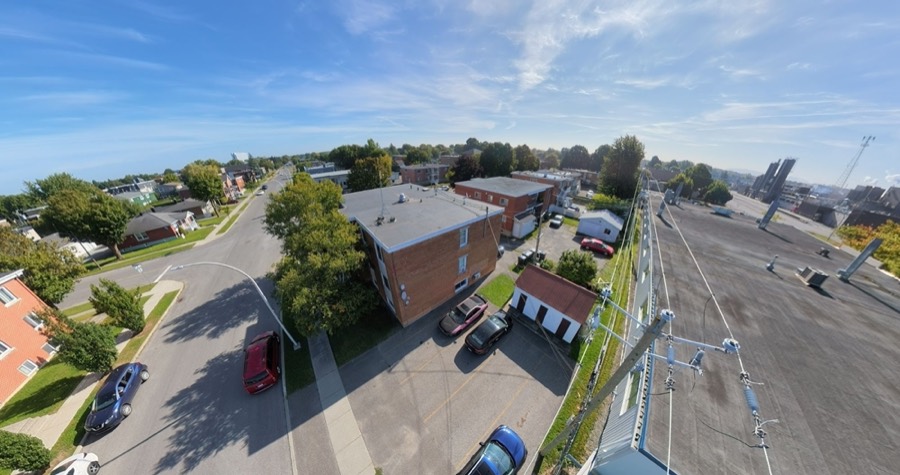 Vue aérienne d'un immeuble de briques et de son stationnement, au coin d'une rue